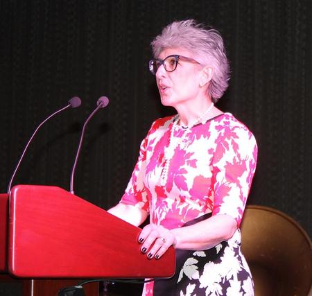 A woman in glasses giving a speech at a podium.