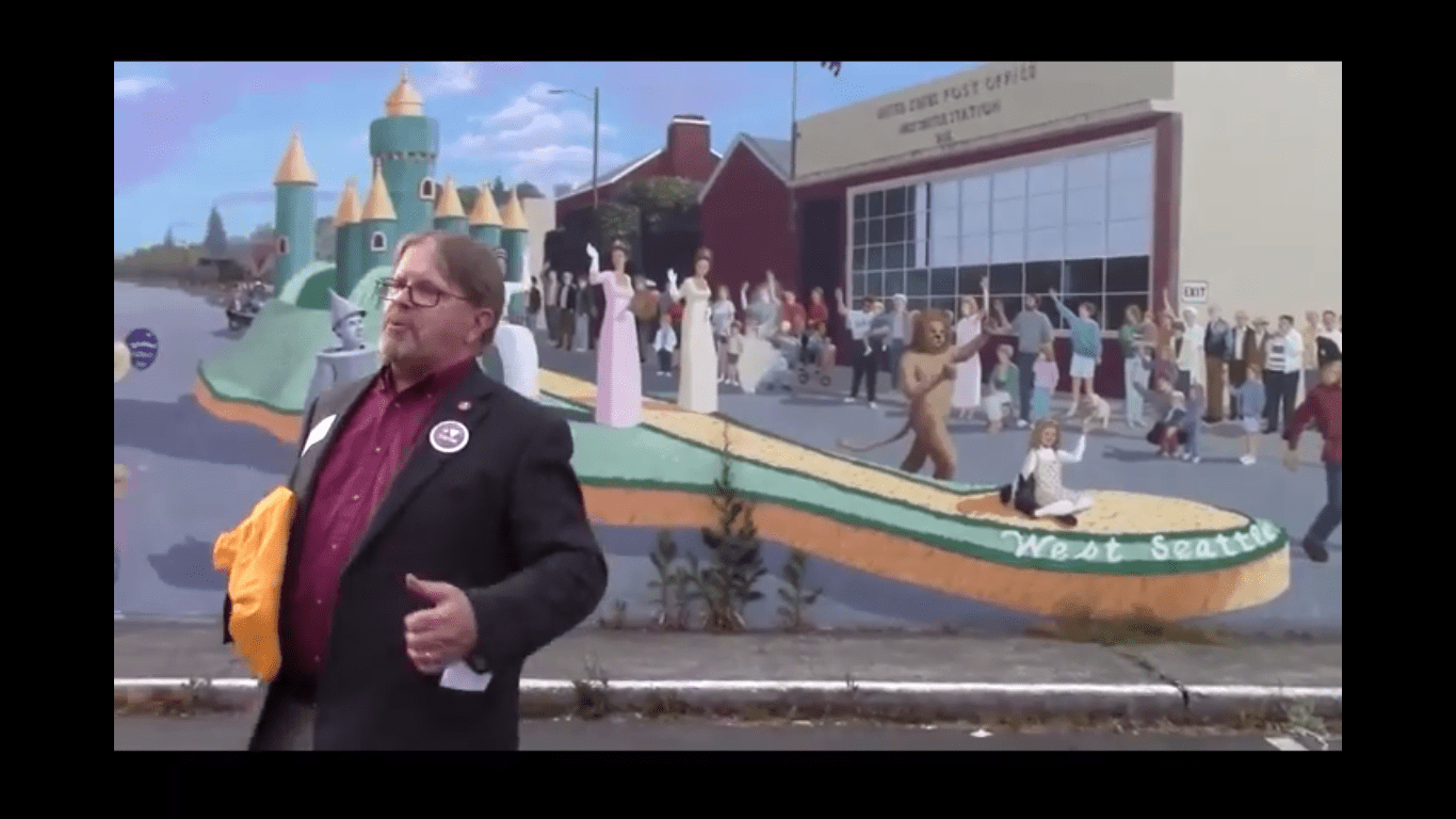 Clay Eals in front of West Seattle mural depicting Morris Beerman's prize winning float